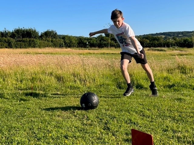 a young Footgolf Devon League player about to kick his football into the field