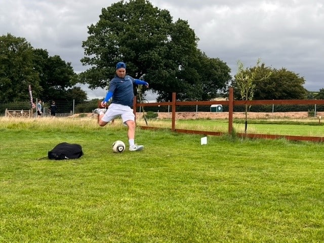 Footgolf Devon player midway through kicking the football into the field